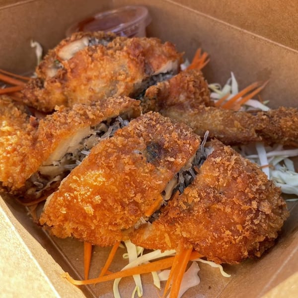 Crispy fried chicken pieces and shrimp, served over shredded cabbage and carrots in a takeout container.